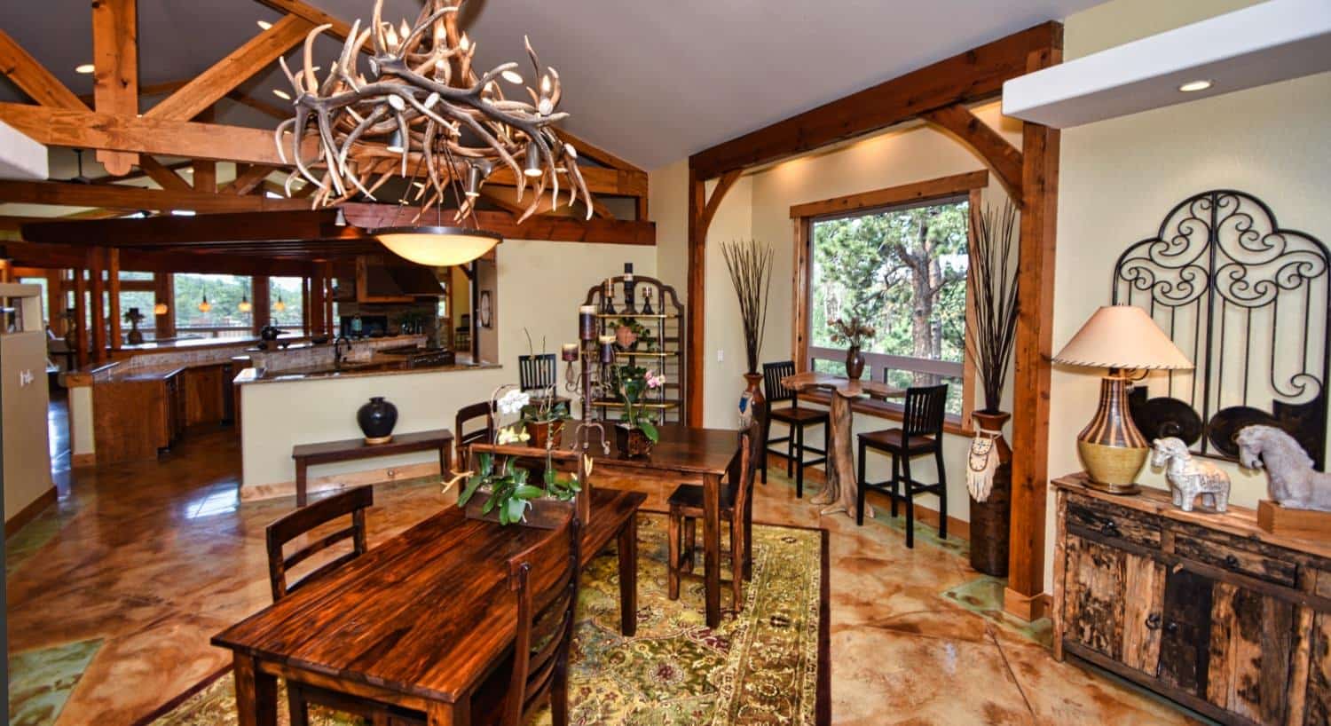 Large dining area with stamped concrete flooring, antler lighting feature, and large window to the outside