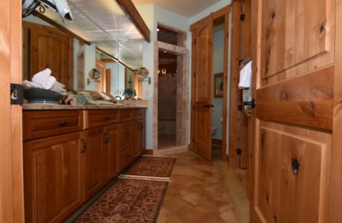Large bathroom with wooden vanity and doors and large walk in tiled shower