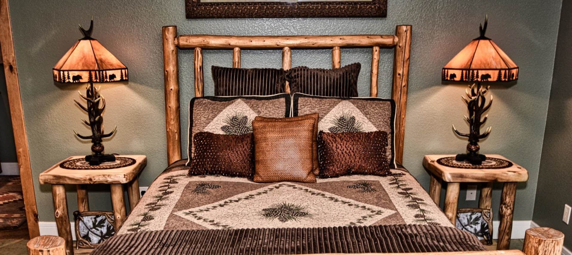 Bedroom with knotty pine bed with brown and gold accent pillows and two end tables with antler lamps
